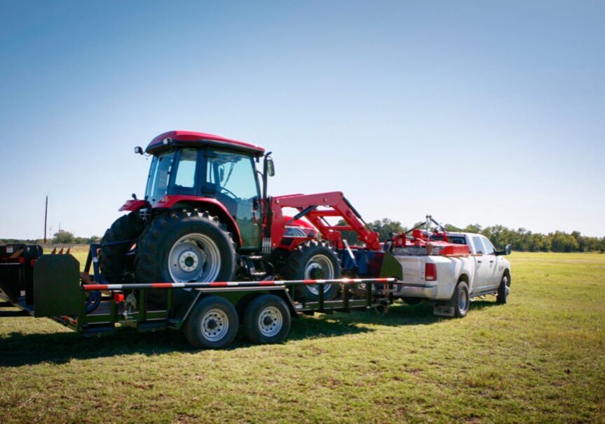 Texas farming: delivering/towing a large red tractor.